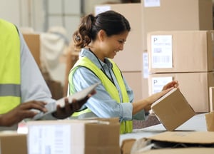 Smiling woman getting a box ready to ship at a fulfillment center