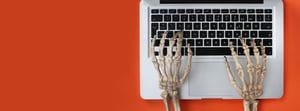 Skeleton hands typing on a laptop computer