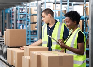 Two workers wearing yellow safety vests check boxes at a third-party logistics (3PL) warehouse